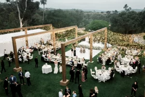 Rancho Valencia wedding lighting with twinkle canopy and wood frame structure over outdoor reception lawn