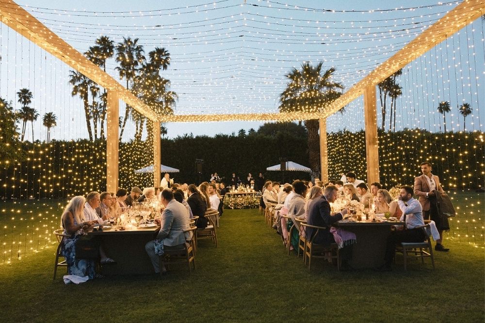 Parker Palm Springs wedding lighting featuring a glowing twinkle light canopy at night, surrounding guests with warm ambient lighting for an intimate reception